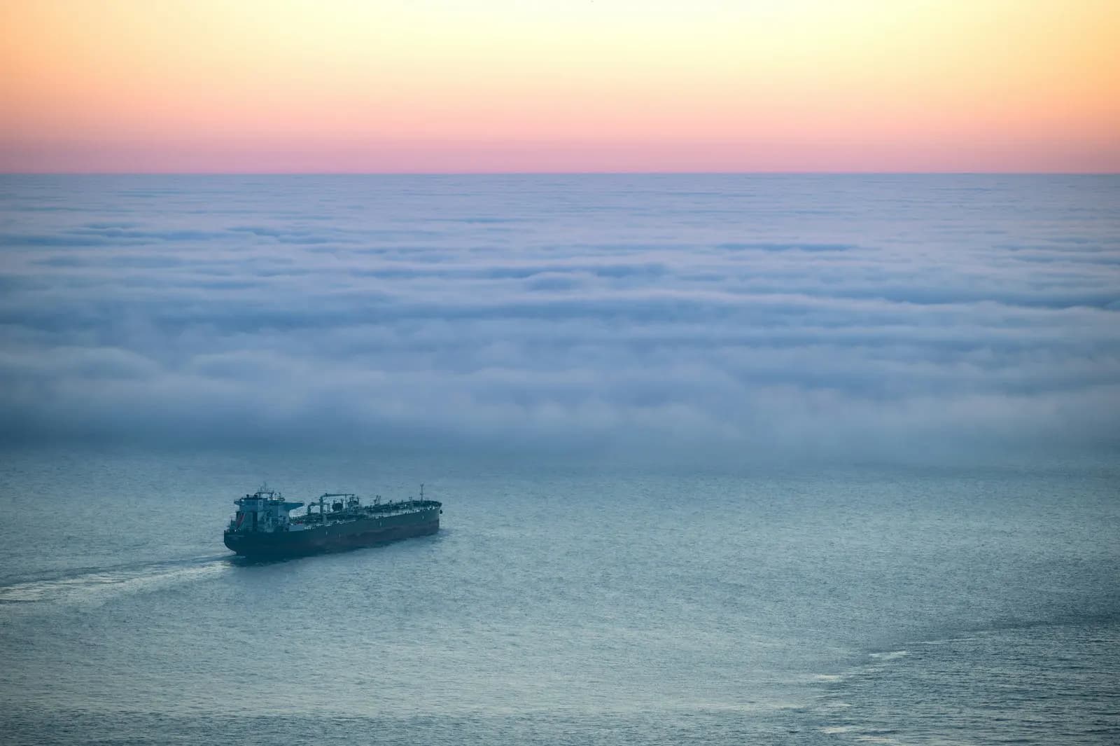 Oil tanker silhouetted against a sunset at sea