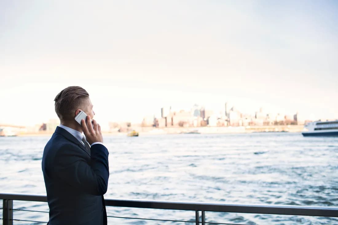A shipping executive taking a call at the waterfront at dusk