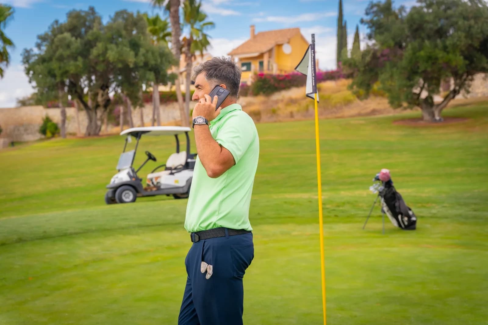 A manager takes a call on a golf course, mid-round