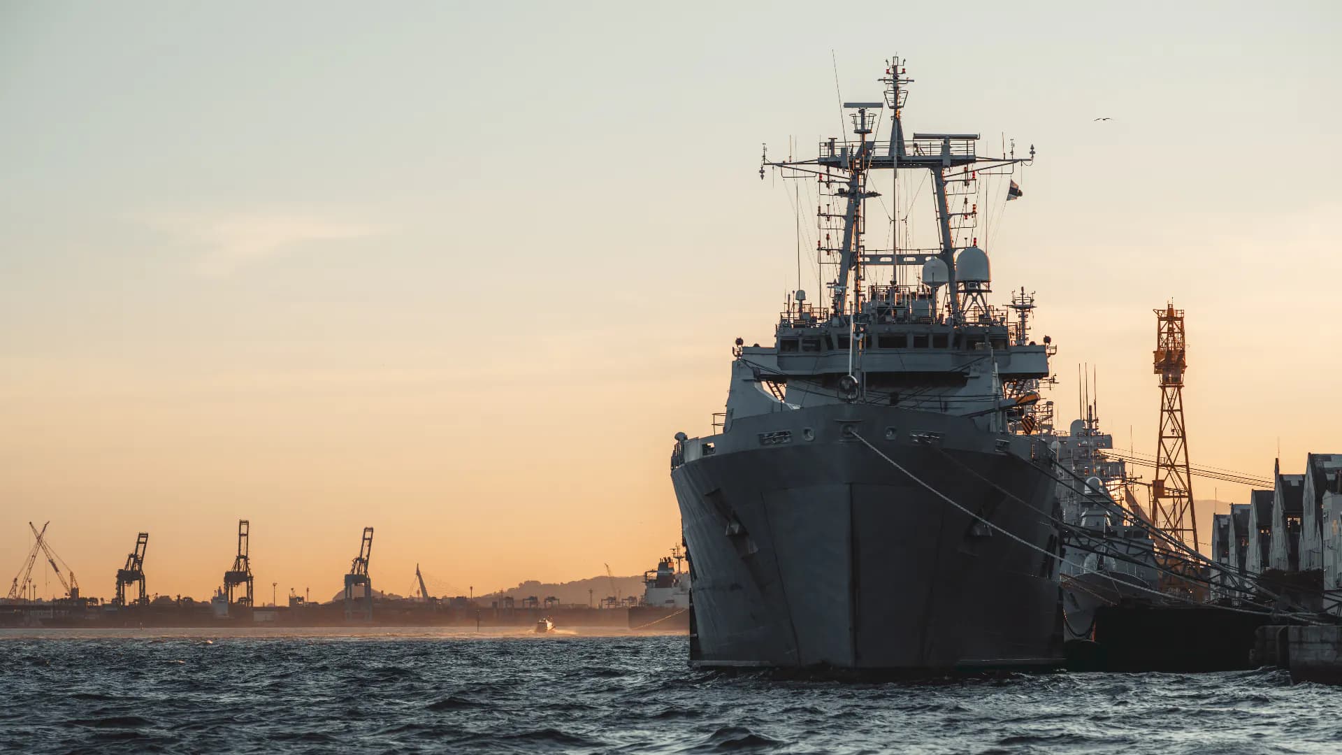 Warship alongside at sunset, illustrating naval enforcement operations in the Mediterranean