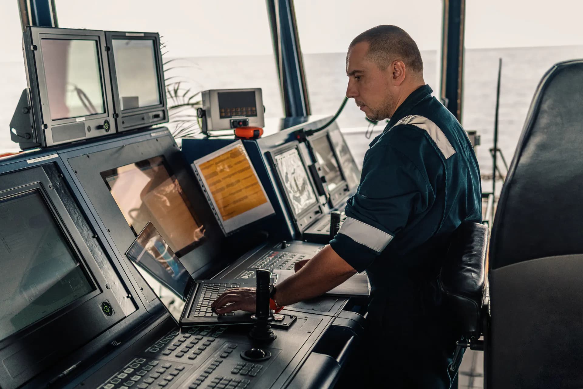 Deck officer working at a laptop aboard a cargo vessel