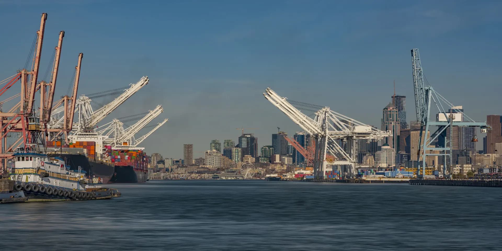 A cargo ship alongside cranes in a busy port
