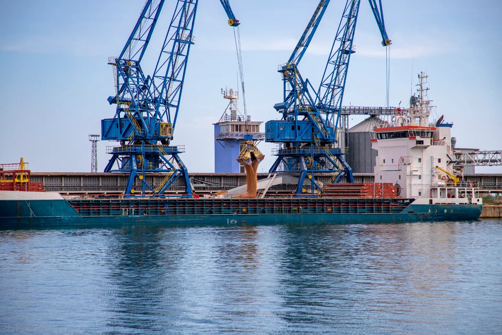 Bulk carrier loading grain alongside a quay in clear weather