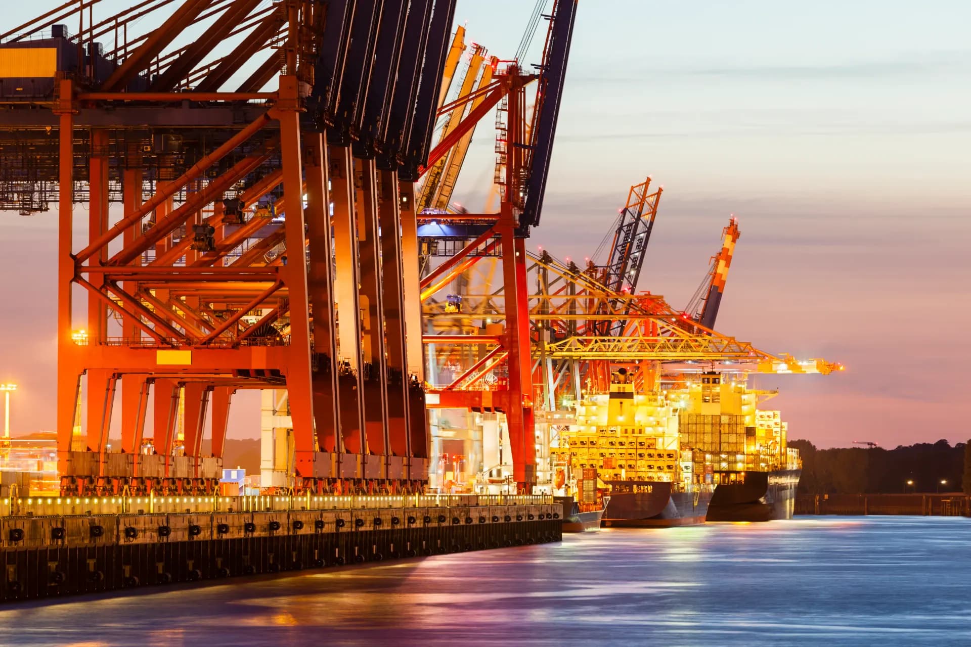 Container terminal lit at night with a vessel alongside