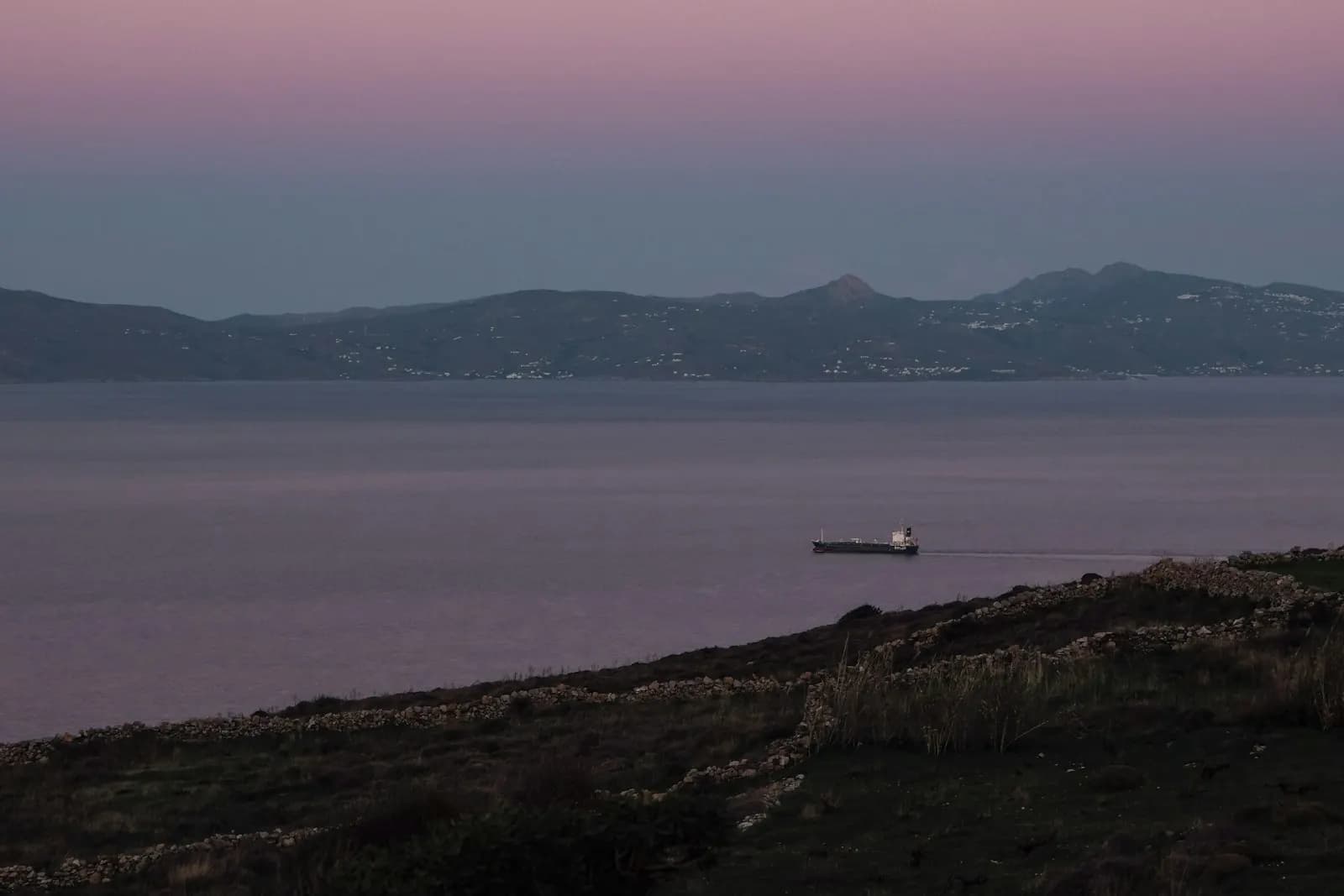 A commercial vessel underway on open water at dusk