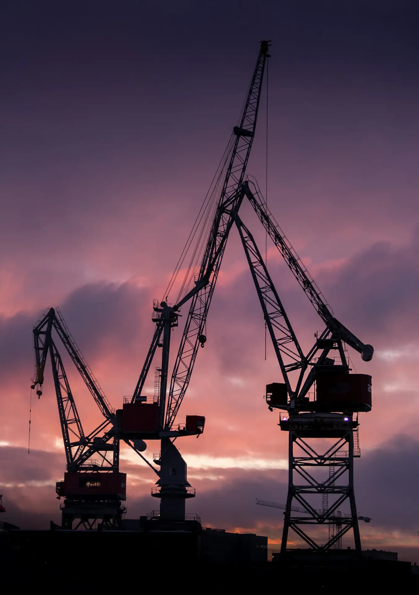 Shipyard cranes silhouetted at sunset