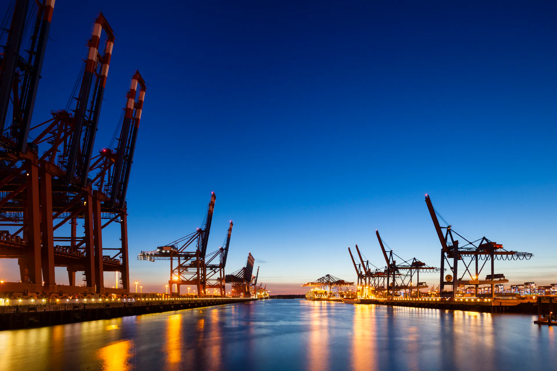 Cranes at dusk in a busy urban port