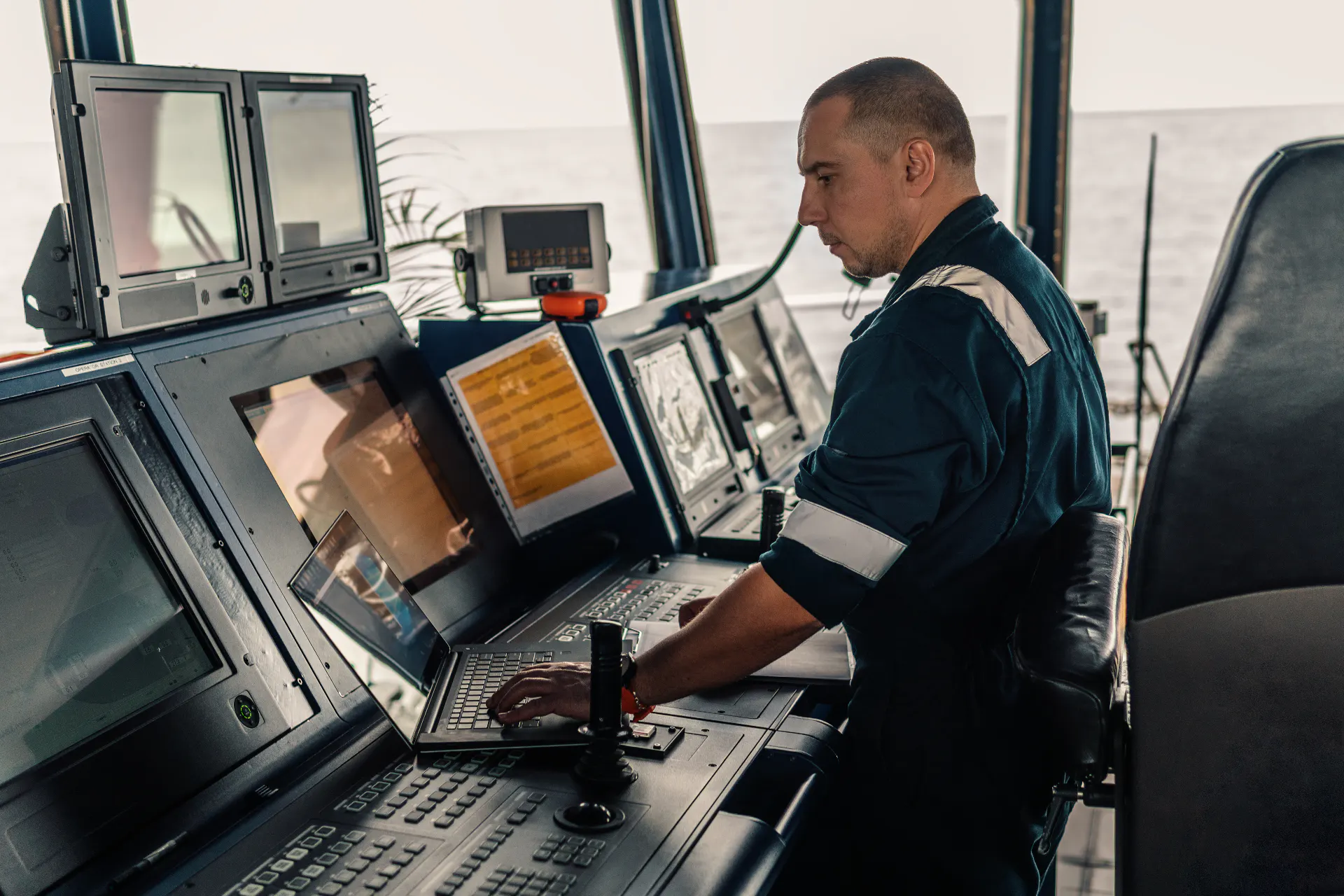 Deck officer working at a laptop aboard a cargo vessel