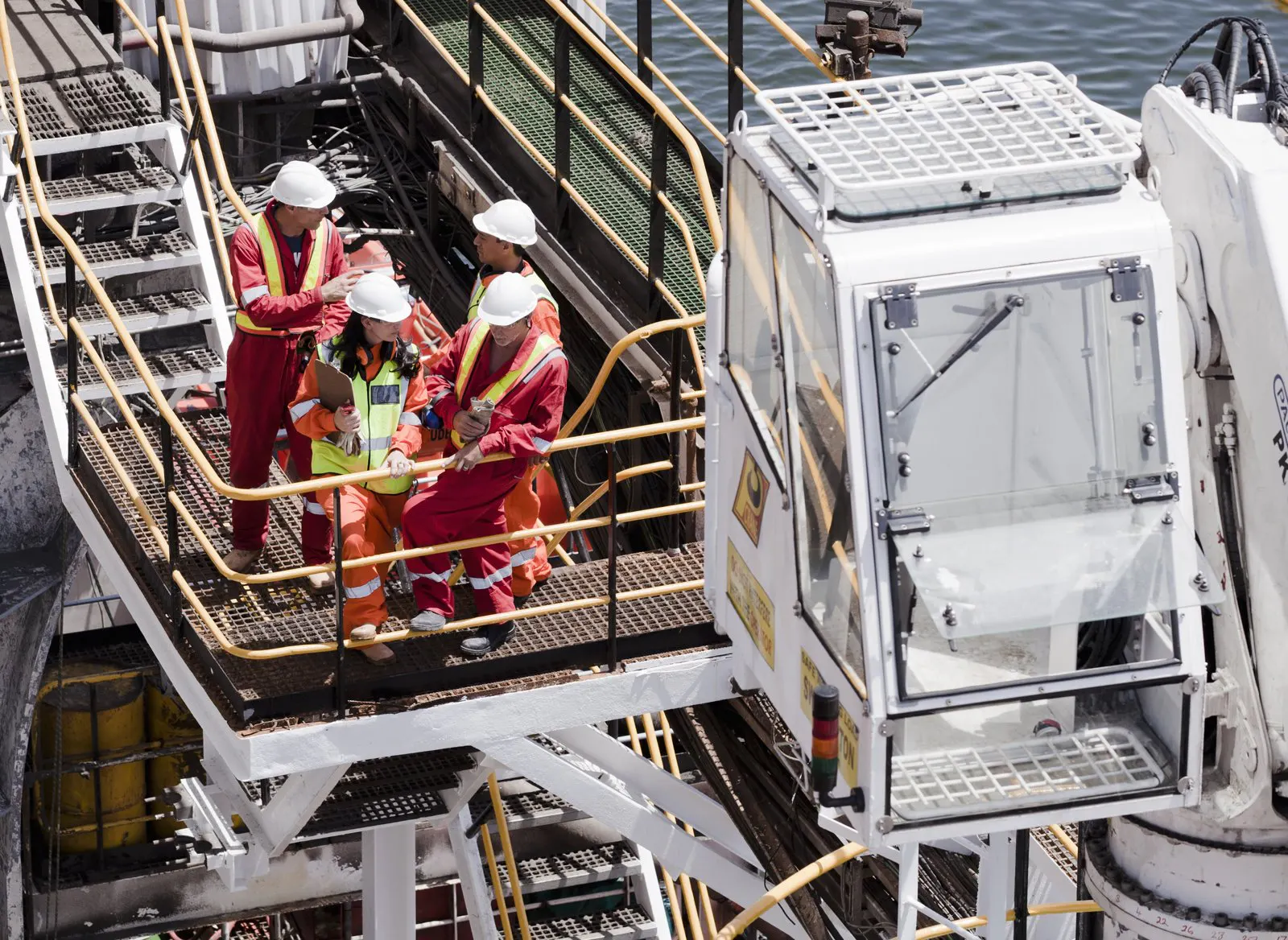 Offshore workers in safety gear near a crane
