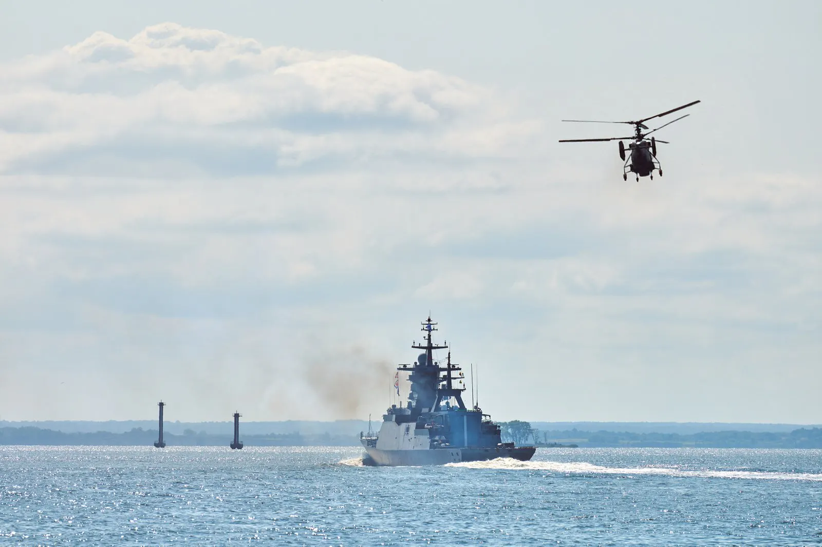 Naval corvette at sea with a helicopter overhead