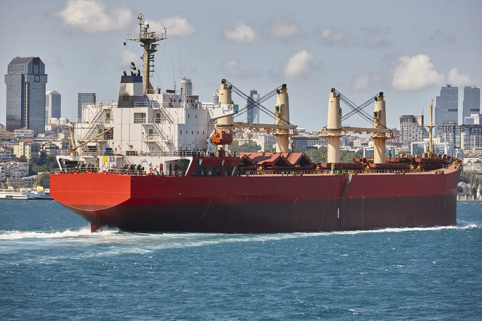 Merchant ship transiting a narrow strait past a city