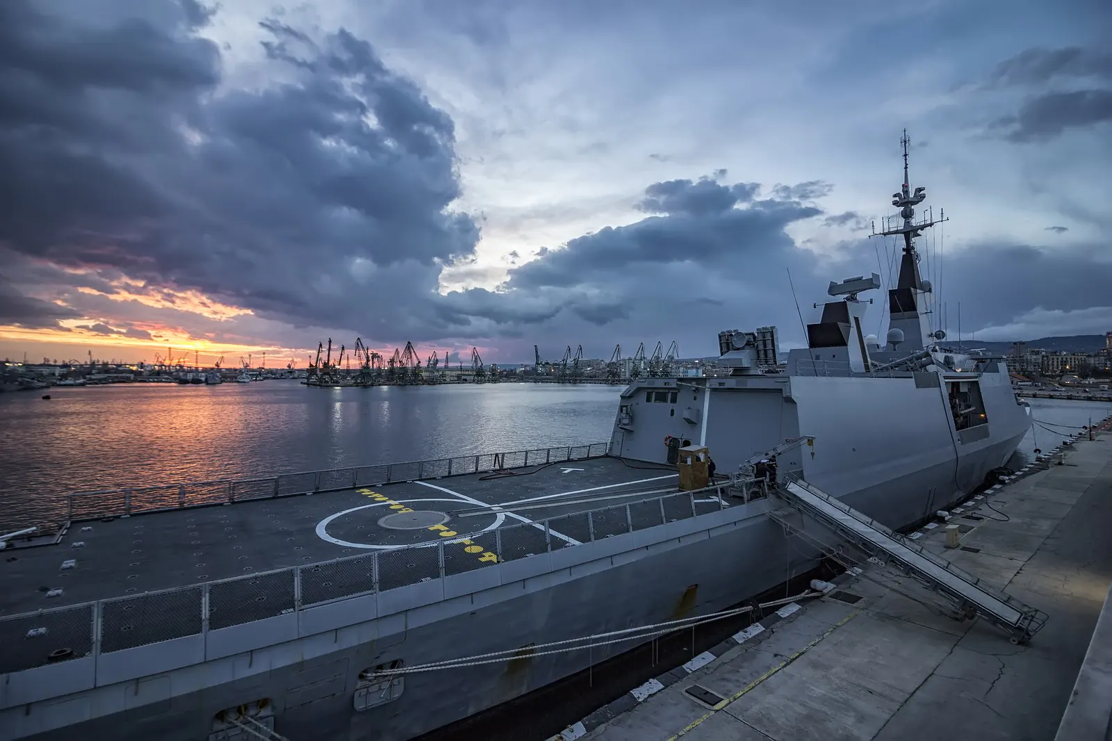 Warship berthed at a naval port at dusk
