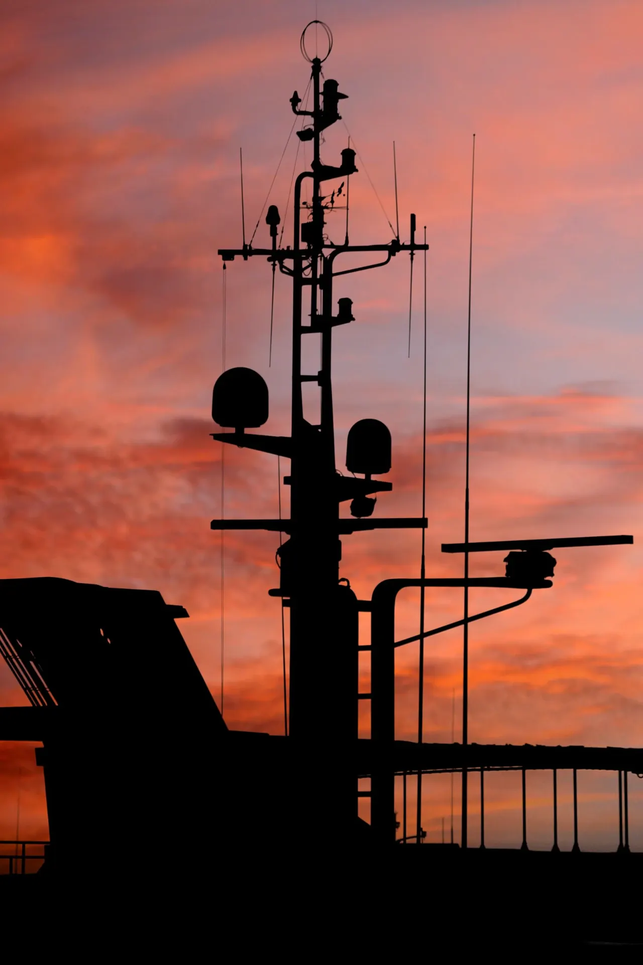 Silhouette of a naval vessel mast against an evening sky
