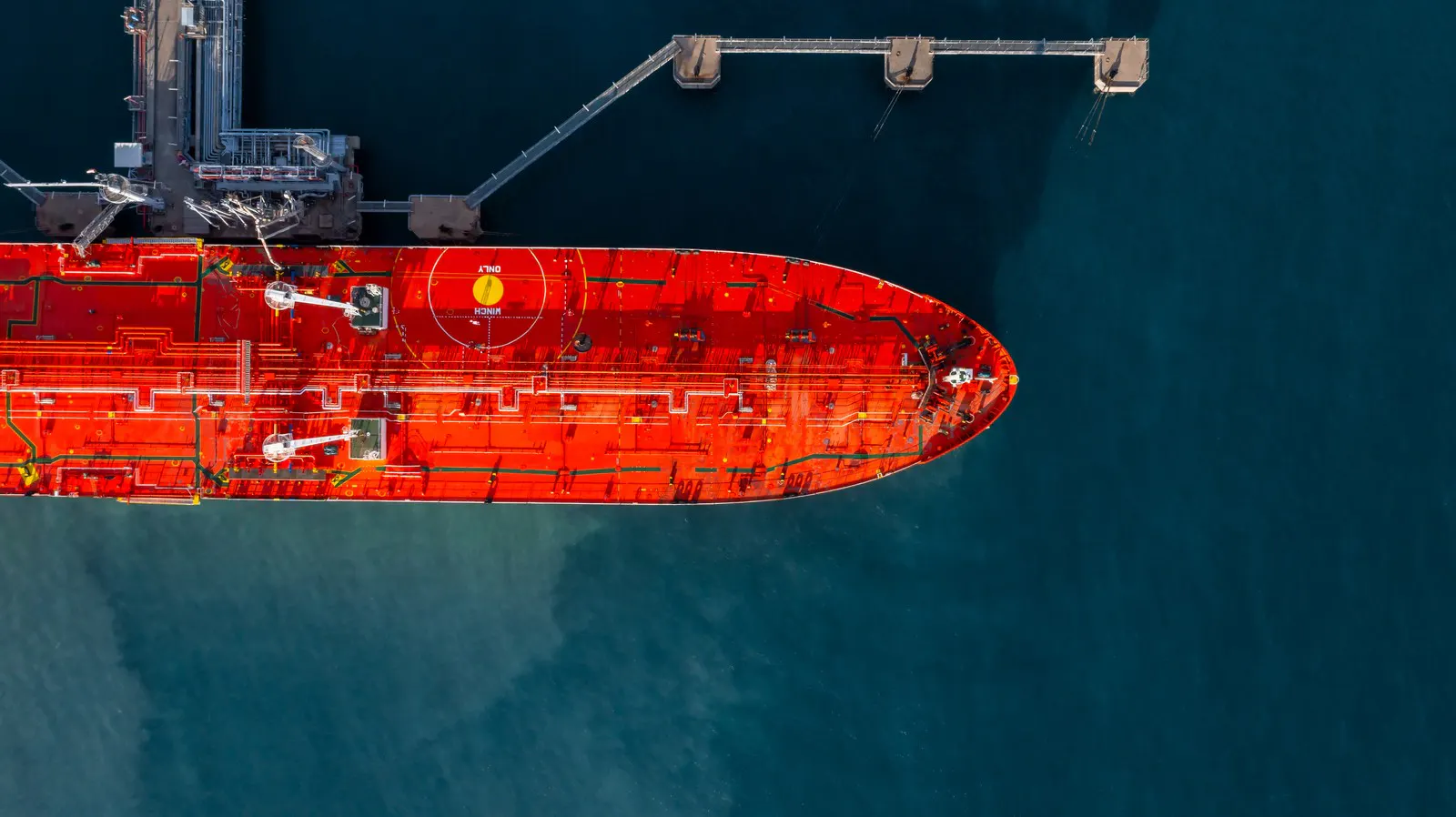 Aerial view of a tanker alongside a coastal oil storage terminal