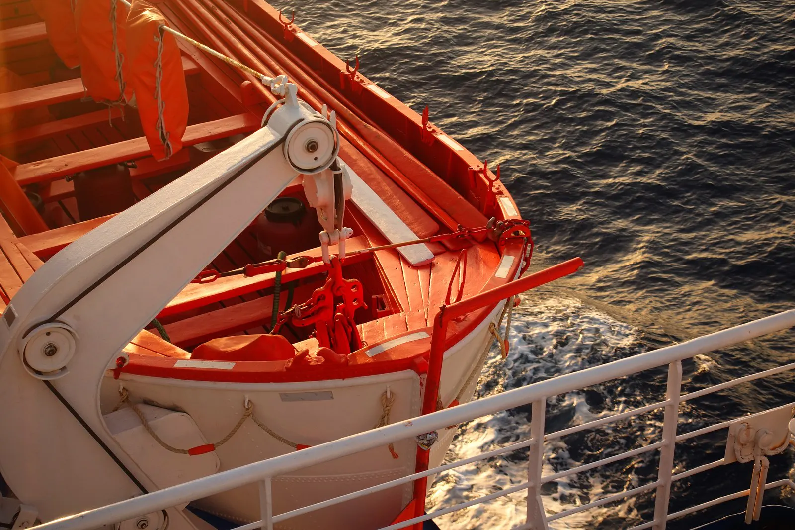 A lifeboat in its davits above the sea alongside a passenger ship