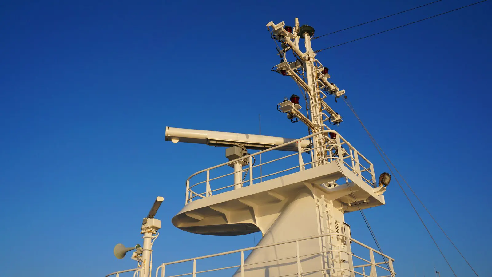 A passenger ship's mast and radar against a blue sky