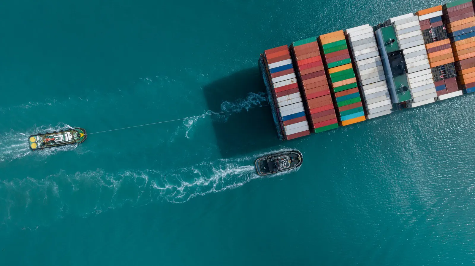 Aerial view of a container ship with tugs alongside