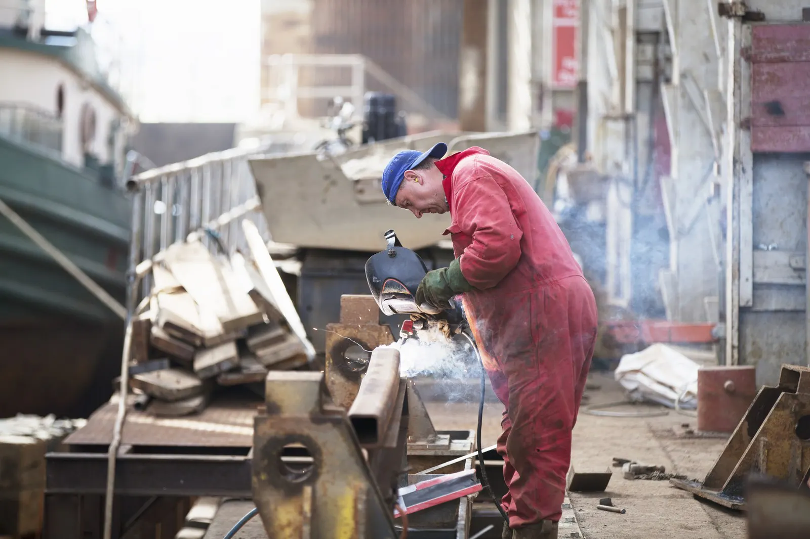 A welder working on a girder in a shipyard workshop