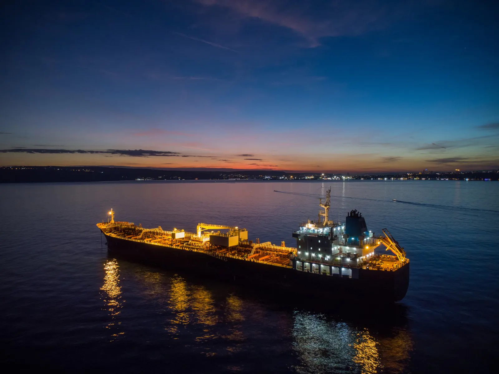 A brightly lit tanker under way at dusk
