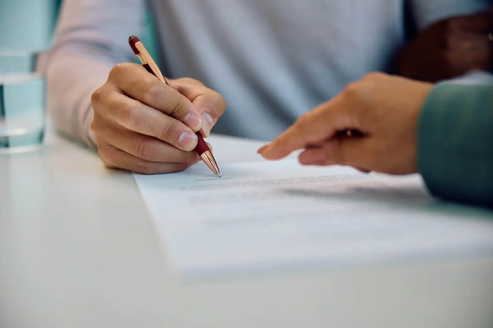 Hands signing a document at a meeting