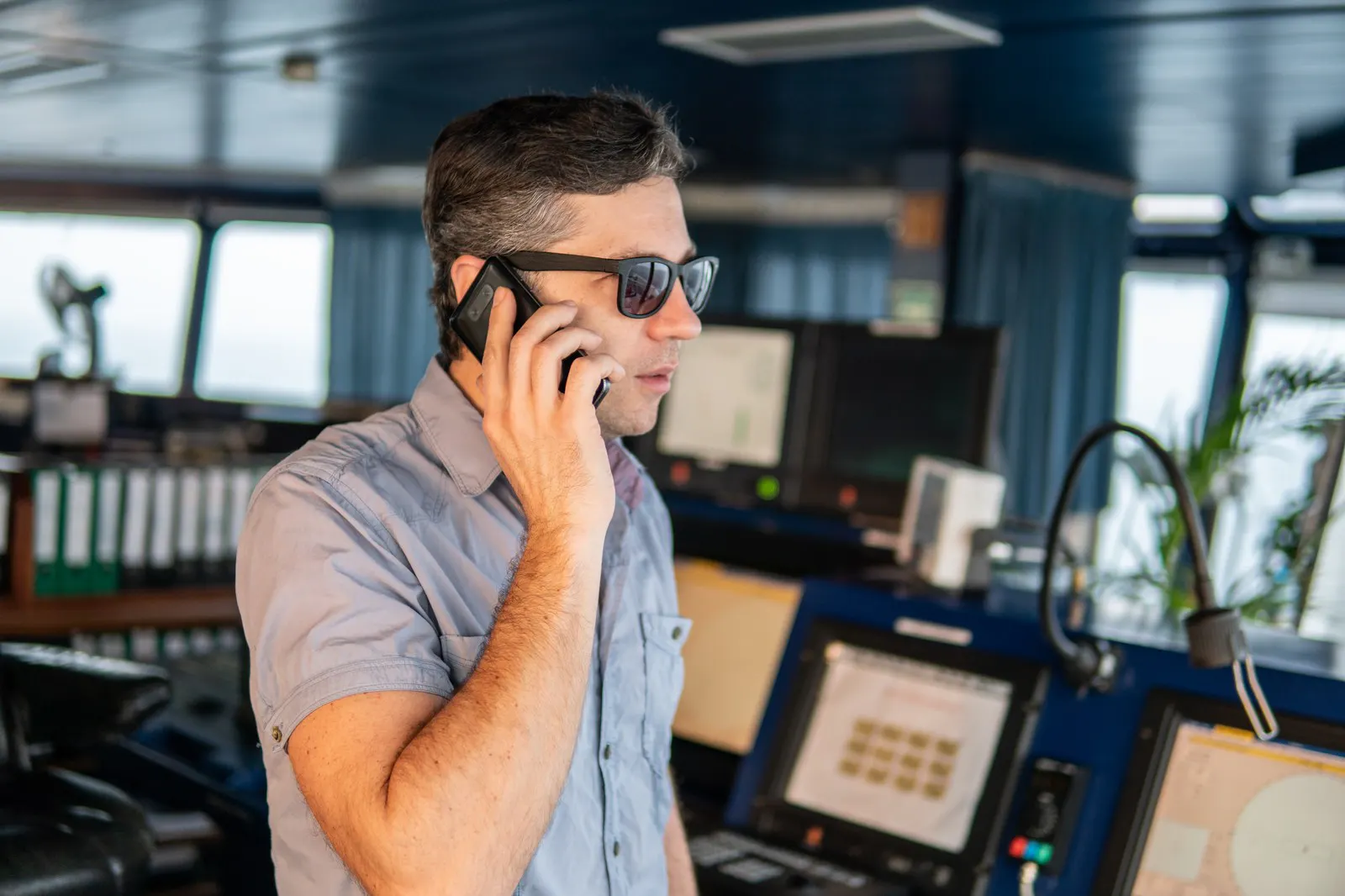 Officer using a mobile phone on a ship's navigation bridge