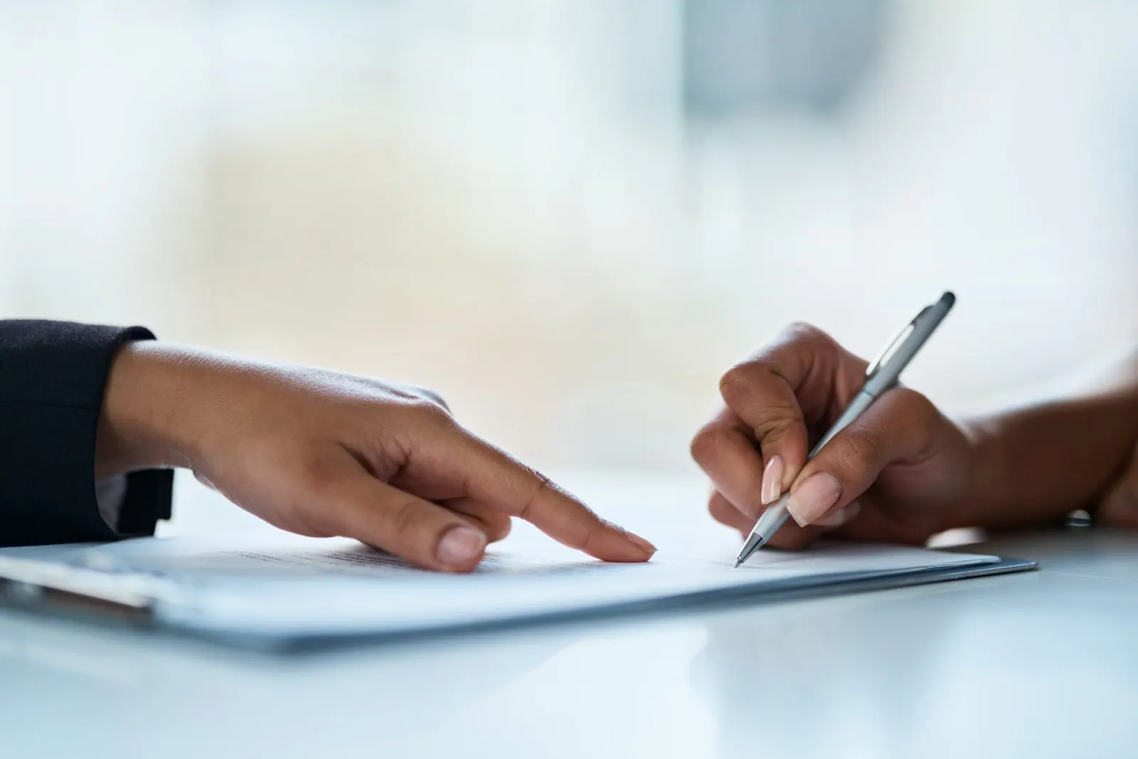 Two people signing paperwork at a desk