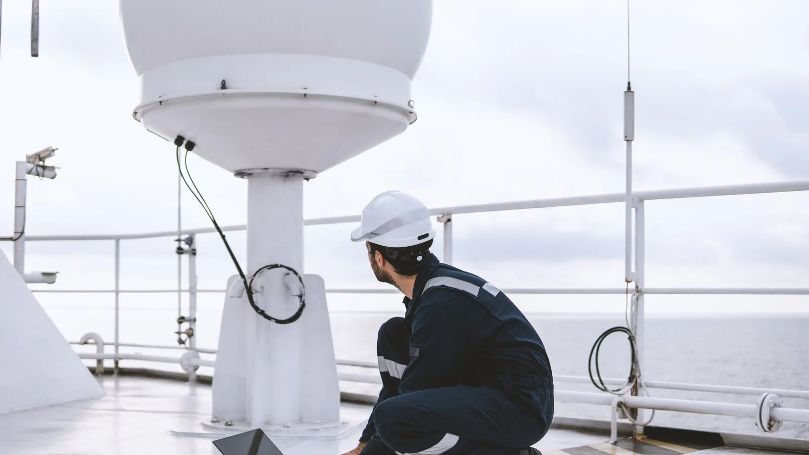Technician working at a satellite communications dome on deck