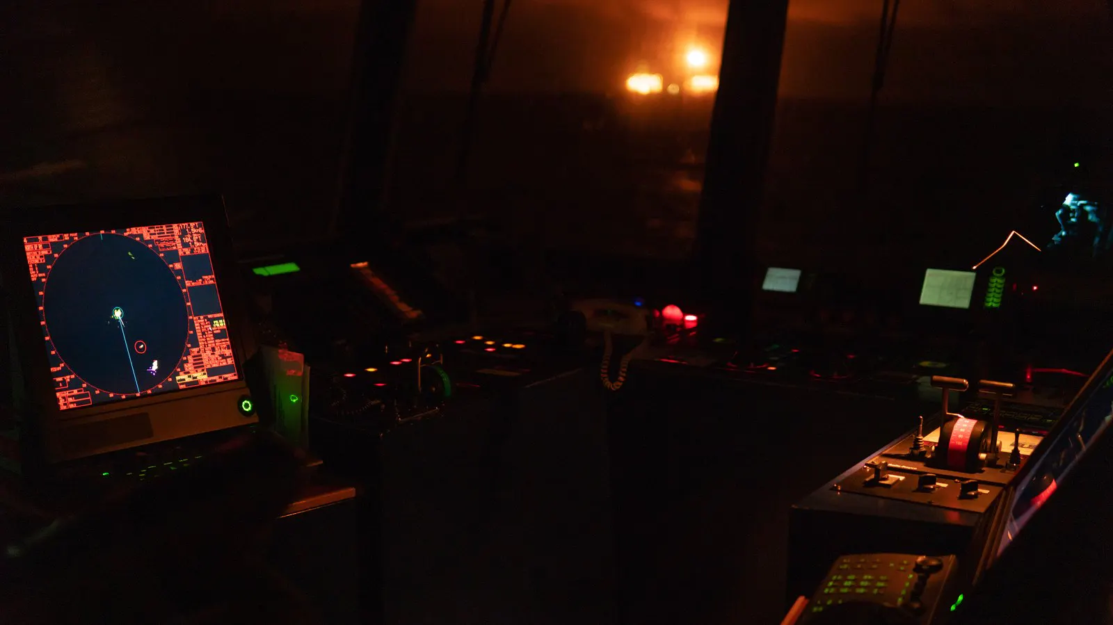 Radar and instrument displays glowing in a darkened ship control room