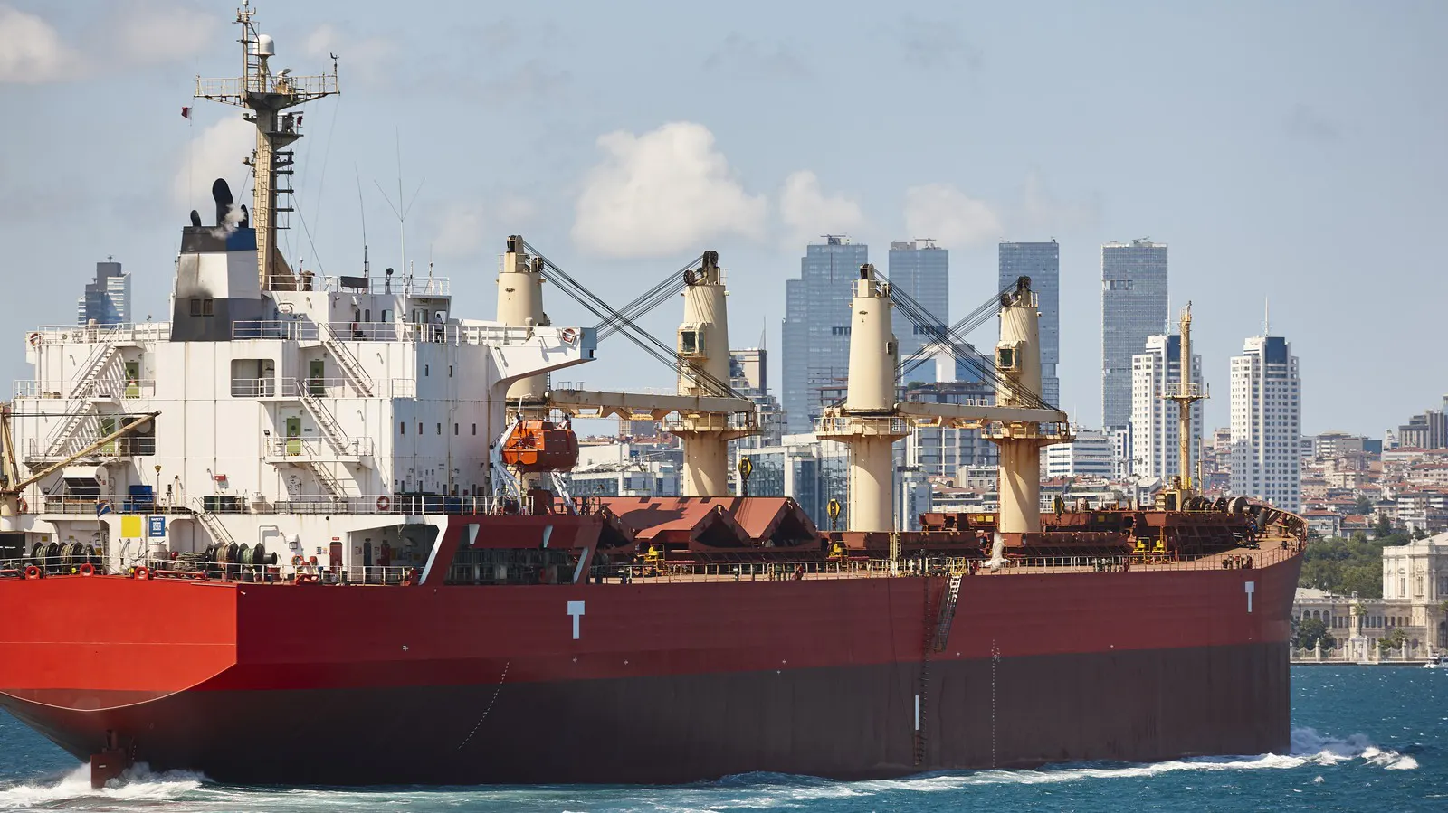 Cargo ship passing a city on a narrow strait