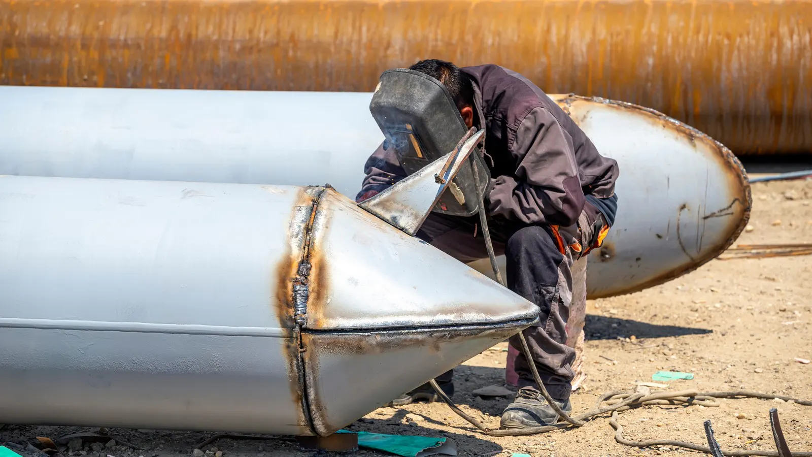 Welder working on large diameter pipe sections