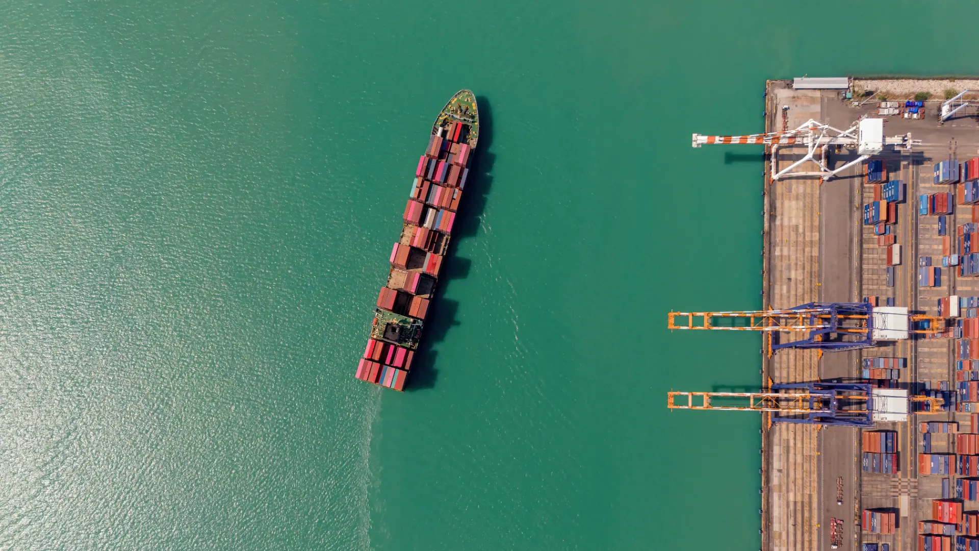 A large container ship seen from directly above at a terminal
