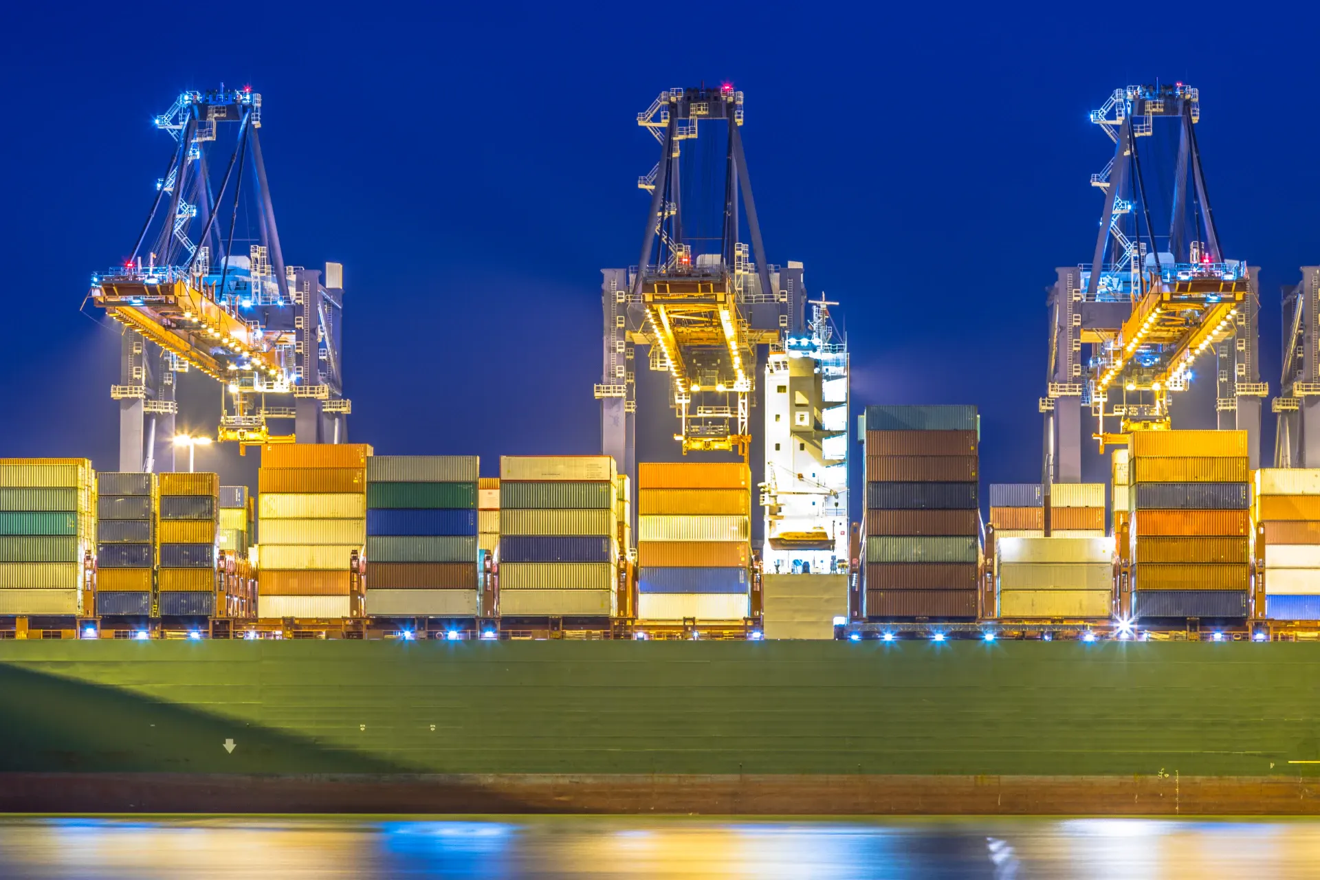 Ship-to-shore cranes working containers under floodlights at night