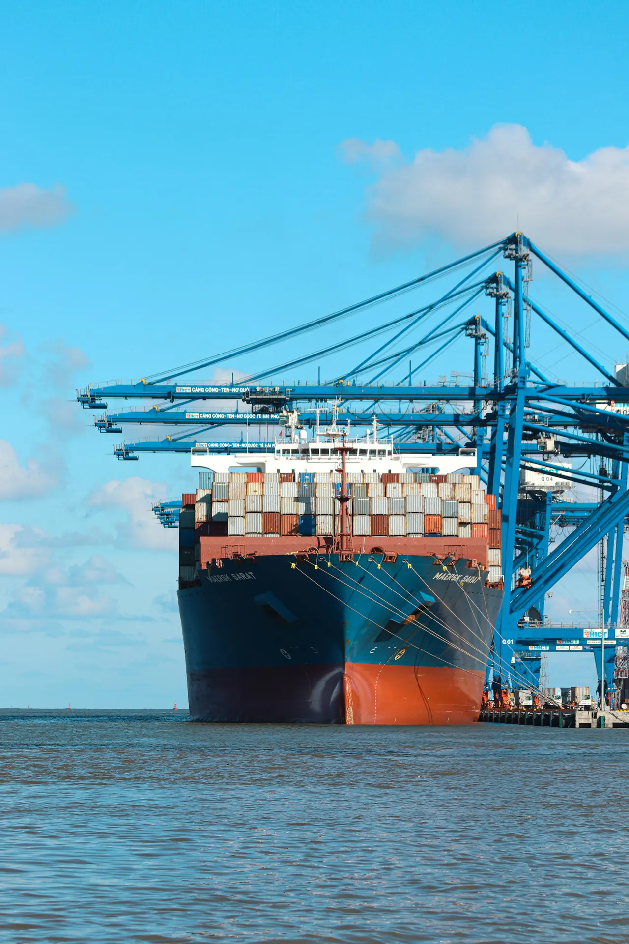 A giant green-hulled containership at a naming ceremony dockside