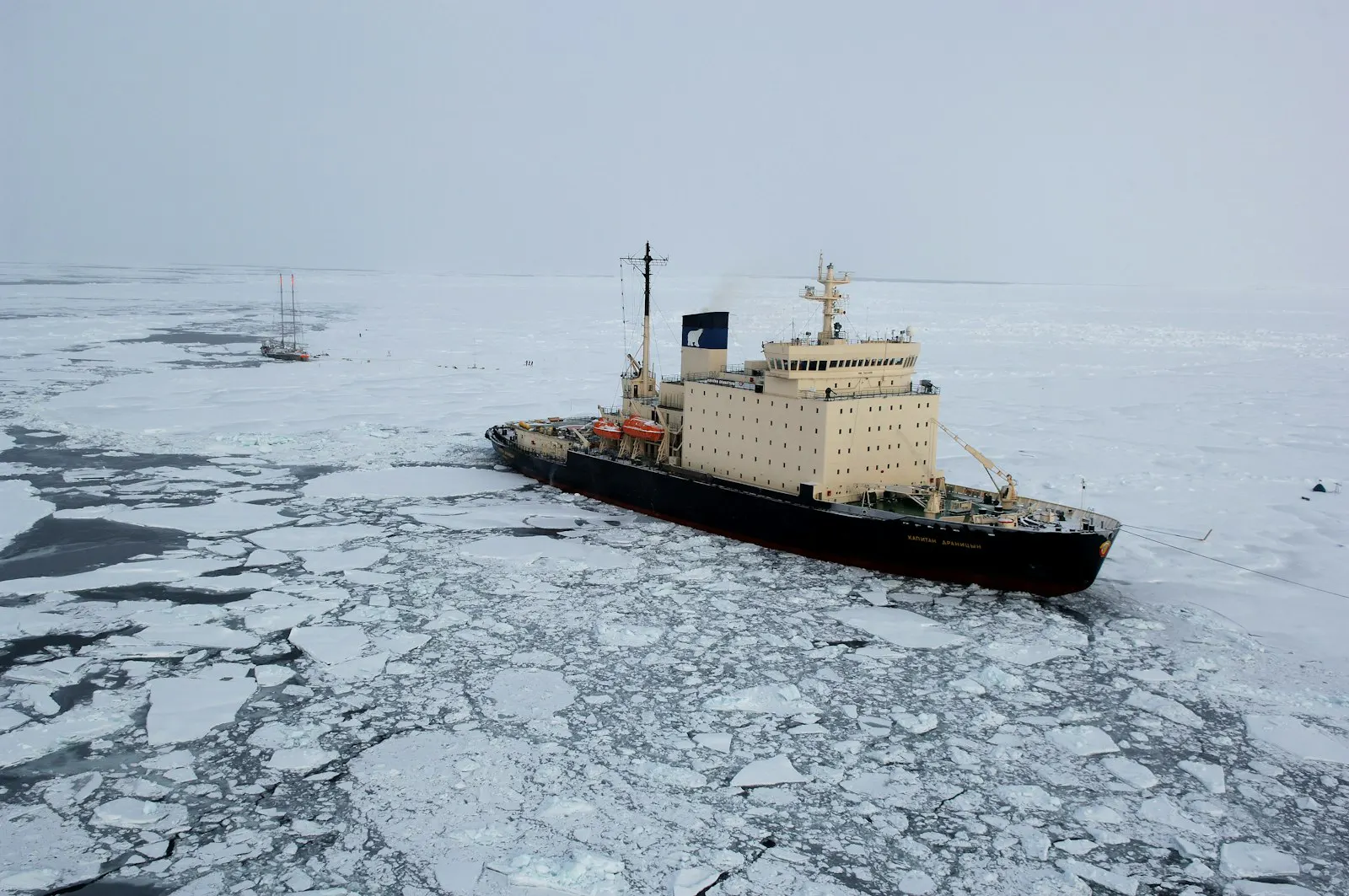 Red-hulled polar icebreaker navigating through ice floes